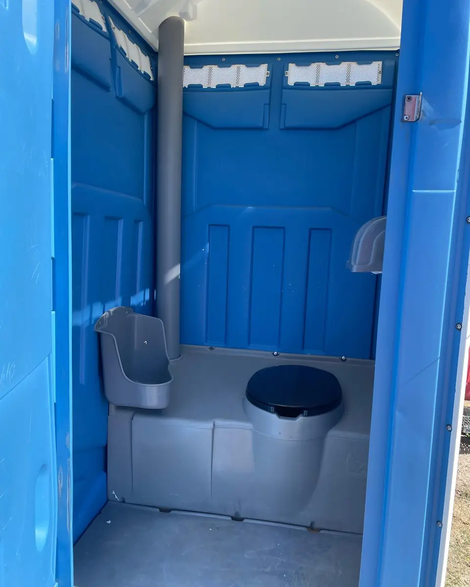 Inside a blue porta potty showing the toilet seat and urinal