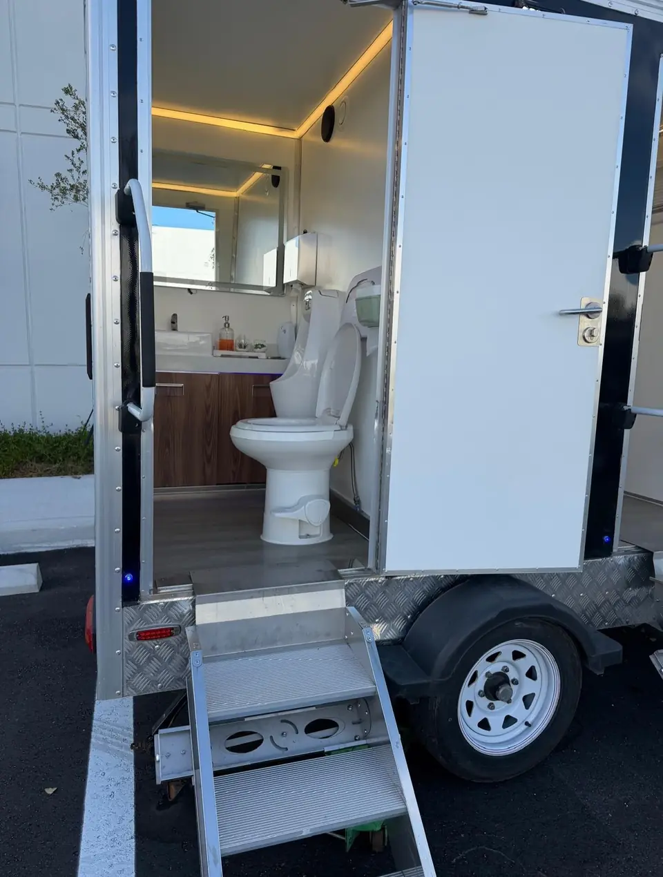 Open stall door inside a larger luxury restroom trailer