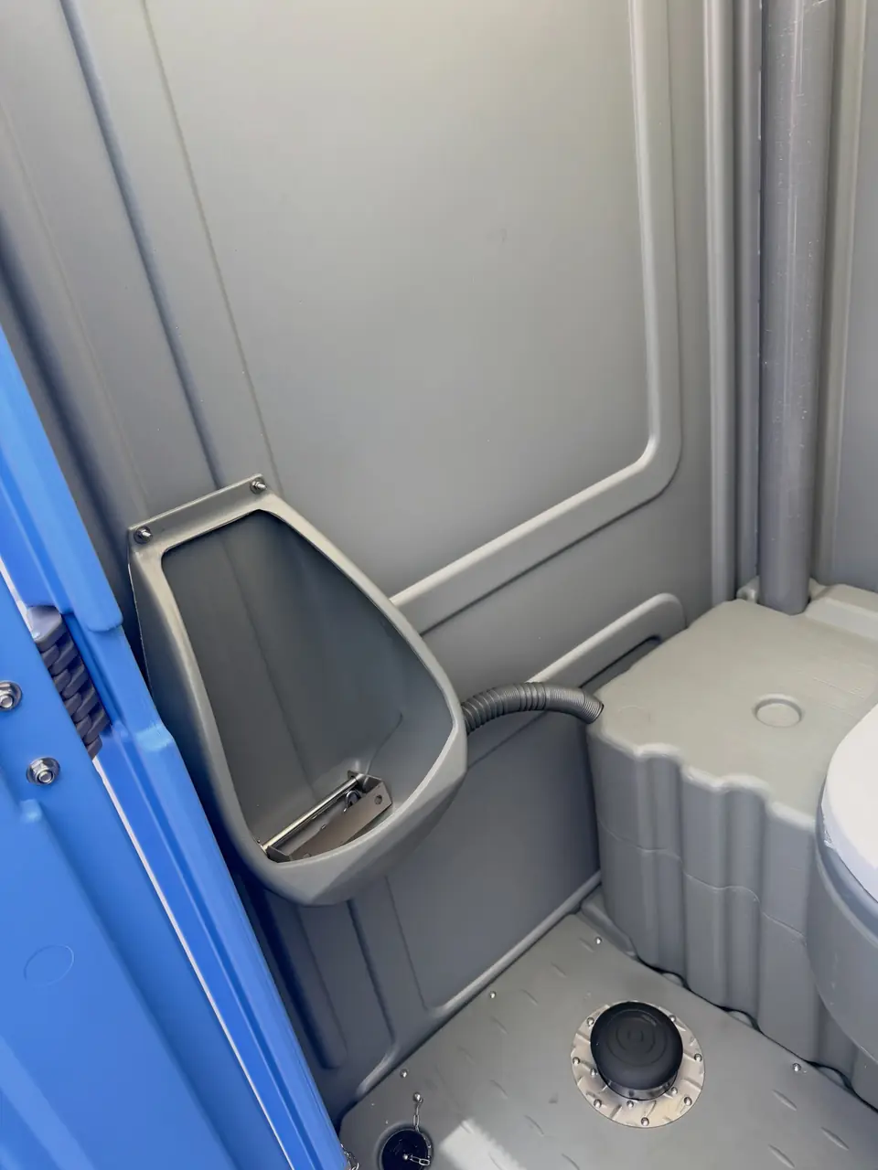 Wall-mounted urinal inside a porta potty