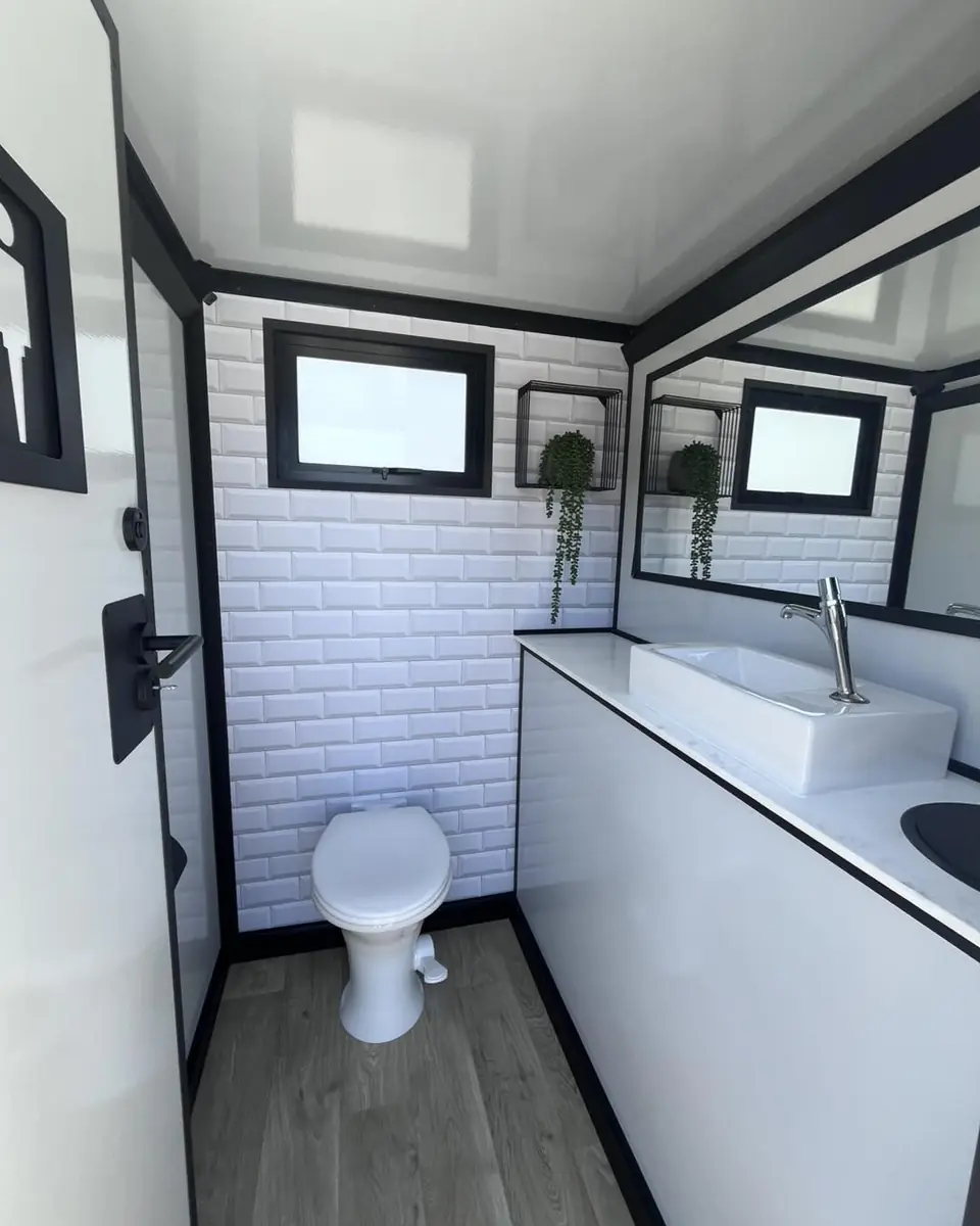 Restroom trailer stall with a flush toilet and vanity