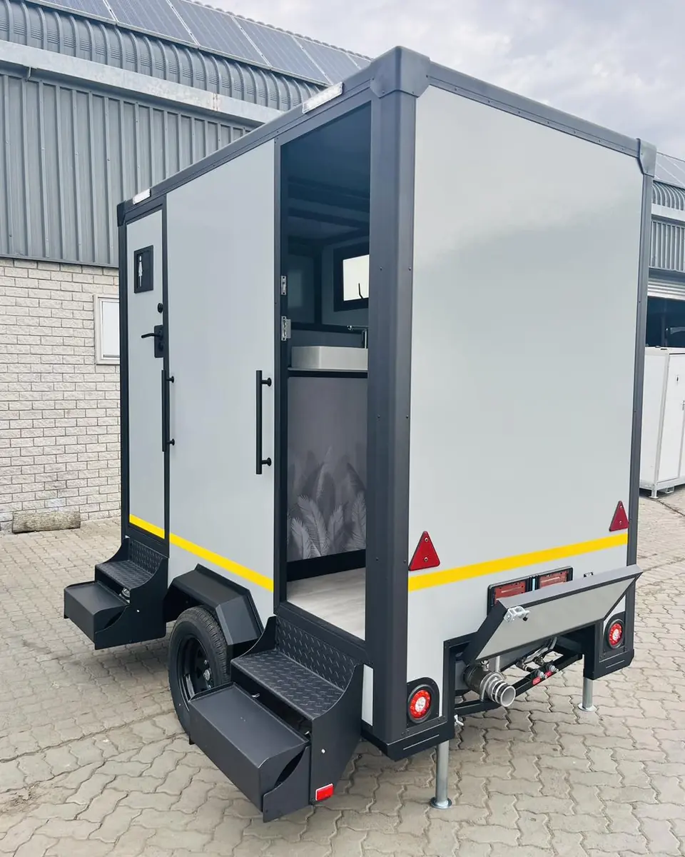 Rear view of a restroom trailer with a door open