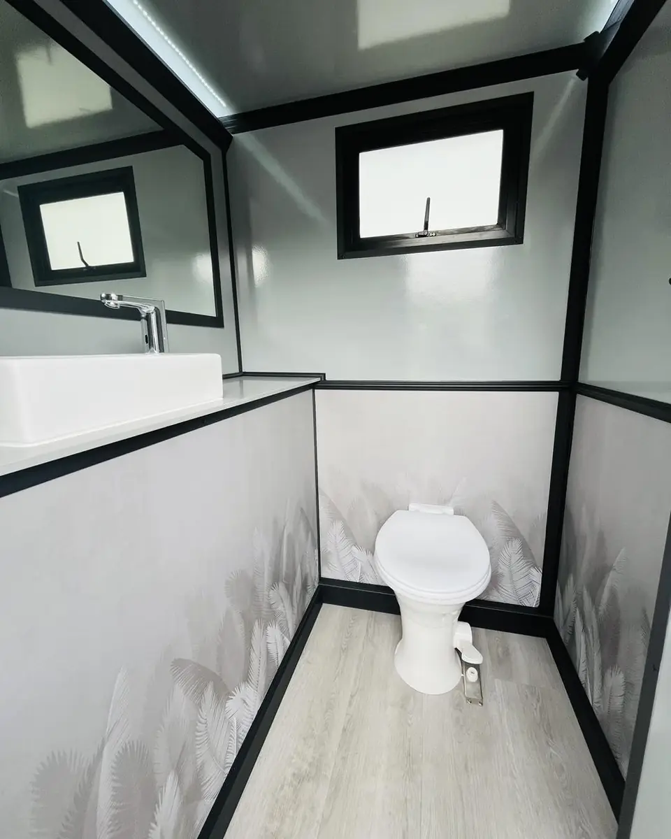 Restroom trailer stall with a toilet under a small window