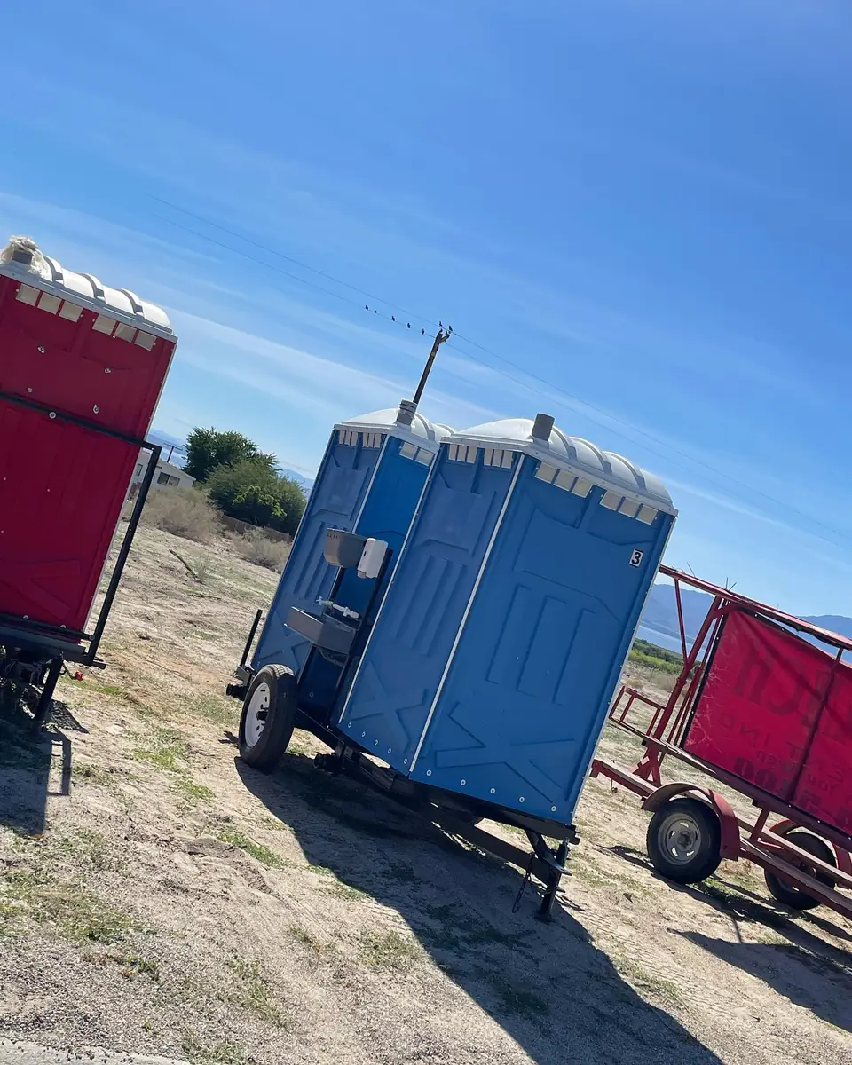 Towable porta potty units on a trailer in a field
